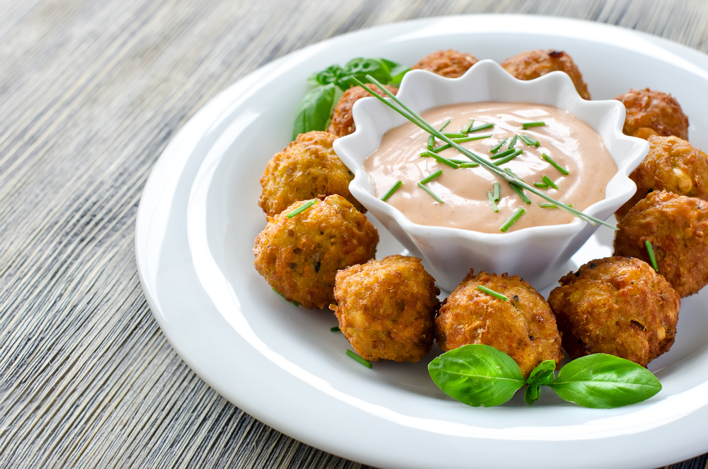 Falafels ready to eat on a plate with sauce and herbs