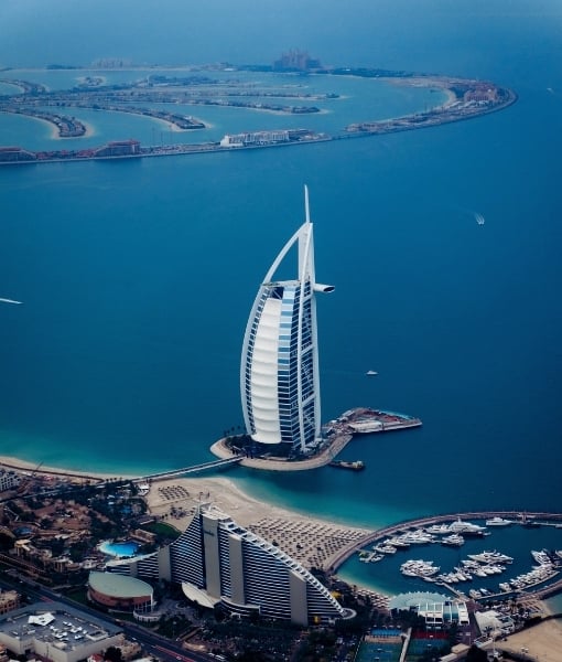 Aerial view of the Burj Al Arab hotel on its private island, with turquoise water and a nearby marina. - Aufgang Travel