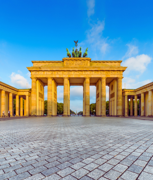 Brandenburg Gate in Berlin with a bright blue sky, the classical columns and rider statues atop, and a wide cobblestone plaza. - Aufgang Travel