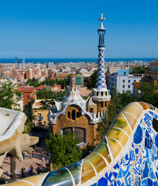 Gaudí-style park scene with a colorful mosaic bench and whimsical towers overlooking Barcelona and the sea. - Aufgang Travel