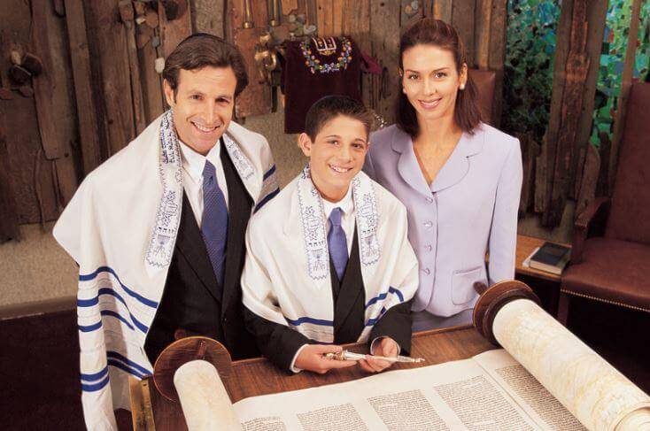 Bar Mitzvah boy with parents reading Torah