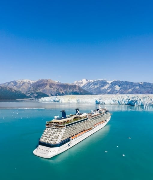 Cruise ship sailing in turquoise water with a glacier and snow-capped mountains in the background. - Aufgang Travel