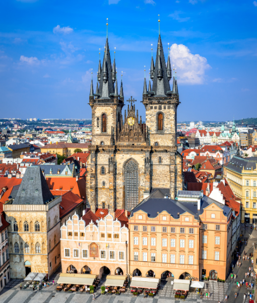 Twin-spired Gothic church rising above colorful Old Town Prague buildings in a busy square. - Aufgang Travel