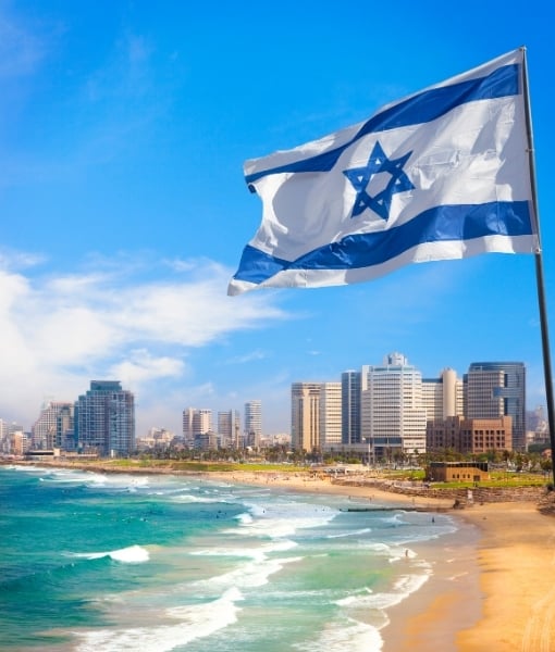 Israeli flag fluttering over Tel Aviv's sandy beach with a city skyline in the background - Aufgang Travel